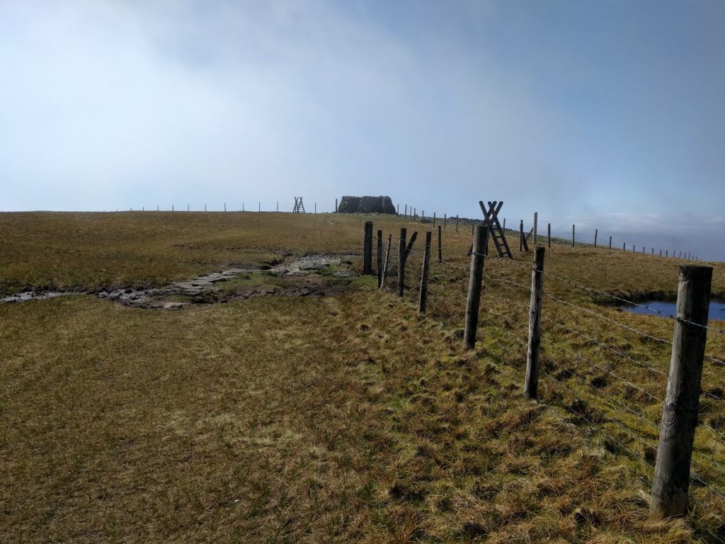 Fence over grassland with stone shelter