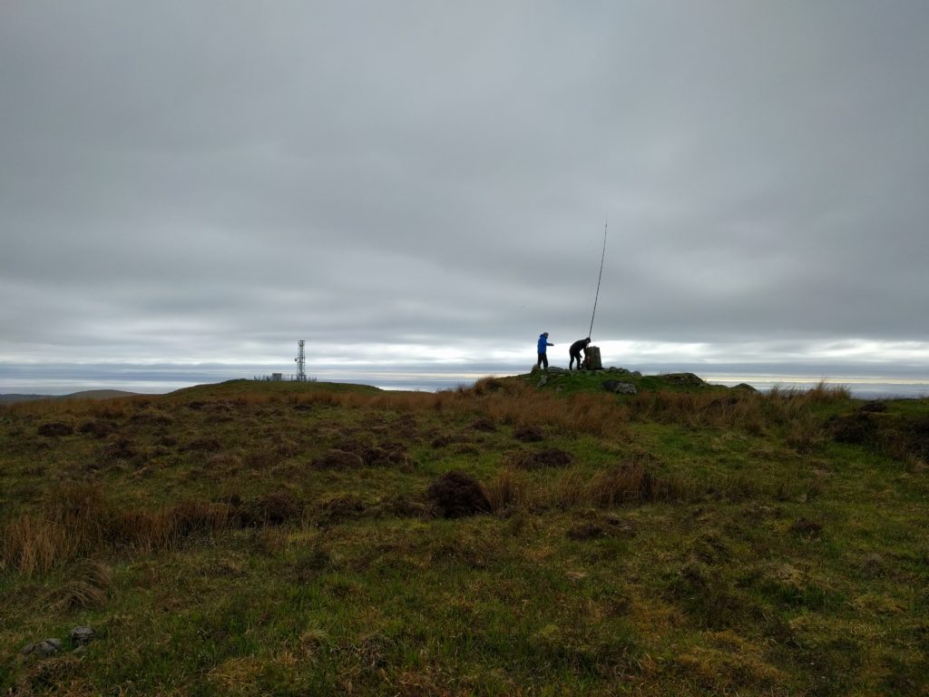 Fibreglass pole at the trig point, with the transmitter site in the background