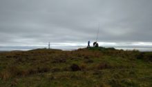 Fibreglass pole at the trig point, with the transmitter site in the background