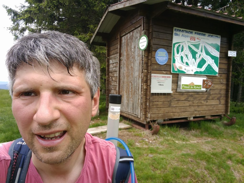 Me by a wooden shelter with signs