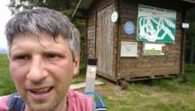 Me by a wooden shelter with signs