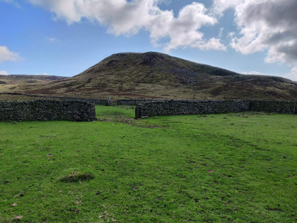 Field with gap in wall and hill behind